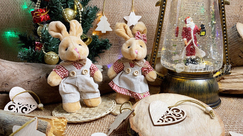 Couple of Christmas rabbits, 2023 animal, New Year tree and magical lantern with Santa Claus on wooden and burlap backgroundÐ± folk style.  Selective focus.
